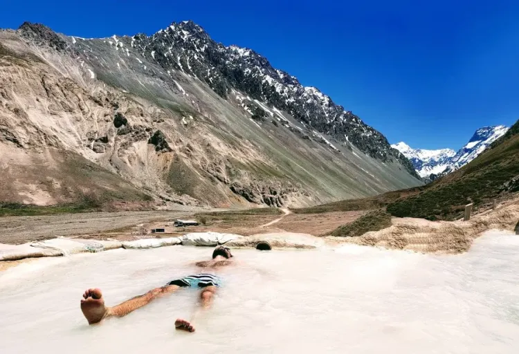 Personas descansando en una poza rodeada de montañas